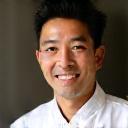 Photo of Chef Kenji Tanaka, a man with a warm smile wearing a chef's coat.